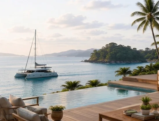 Oceanfront villa terrace with infinity pool, palm trees and a yacht at anchor